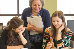 Professor looking over two students at work.